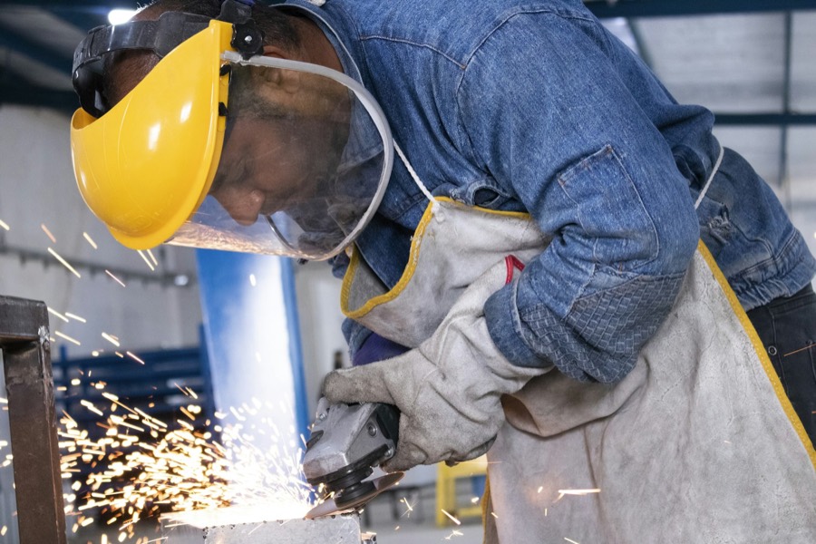 A welder in a shield working a joint, sparks flying.